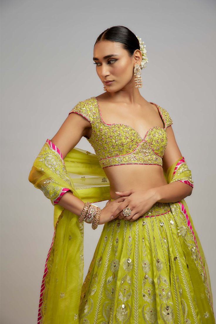 Editor's Note In a vibrant ensemble with exquisite marodi work and sequins, the billowing skirt is paired with a stunning neckline choli adorned with zardosi work. The soft organza dupatta with delicate motifs and borders adds a softer element—a story of love, passion, heritage, and beauty. Lime Green Lehenga, Marodi Work, Zardosi Work, Indian Arts And Crafts, Personal Shopping Service, Fashion Drawing Tutorial, Green Lehenga, Organza Dupatta, Custom Tailoring