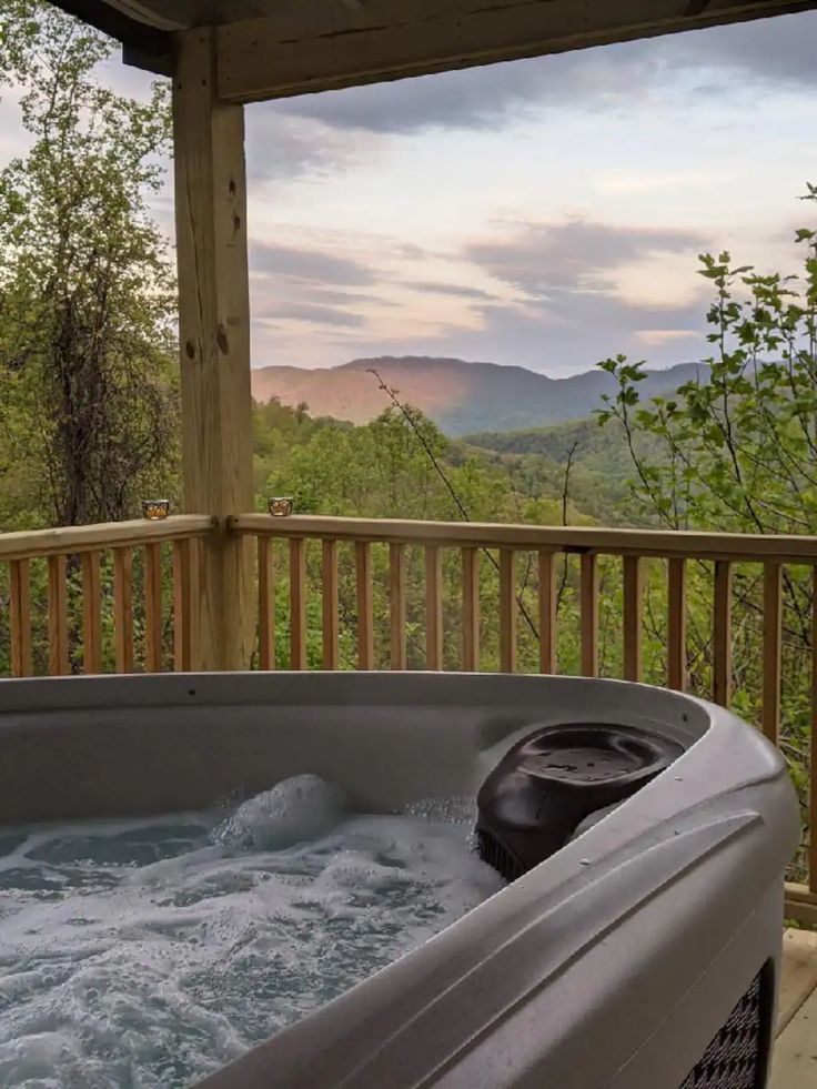 a hot tub on a deck with mountains in the background