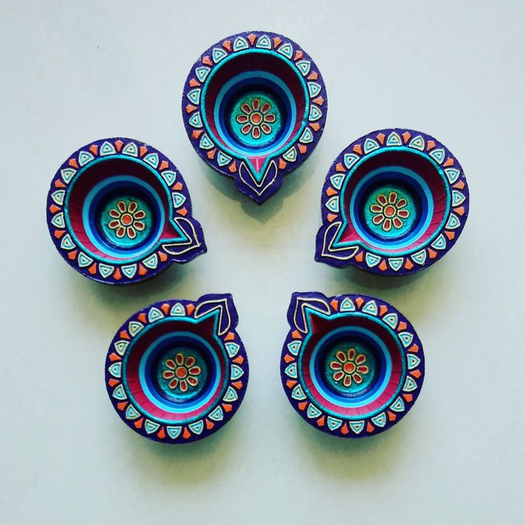 four colorful bowls sitting next to each other on a white counter top with an orange flower in the center