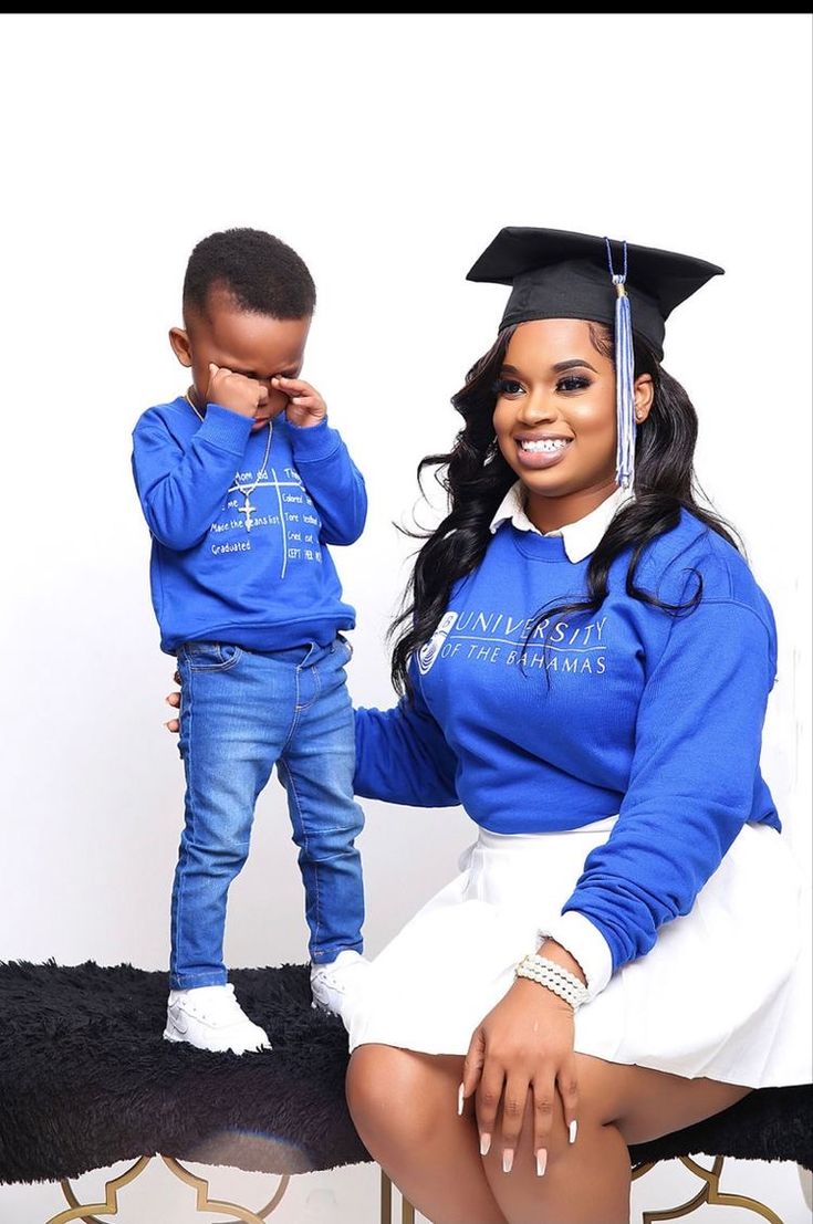 a woman sitting on top of a chair next to a little boy wearing a graduation cap