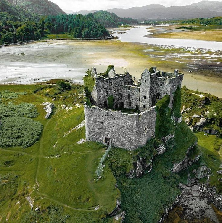 an aerial view of a castle on top of a hill next to a body of water