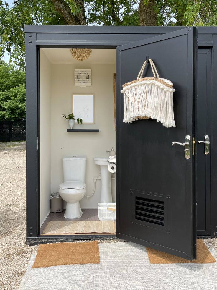 an open toilet stall with a white toilet in the corner and a hanging item on the door