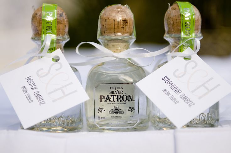 three bottles of patron gin on a table with tags attached to the top one bottle