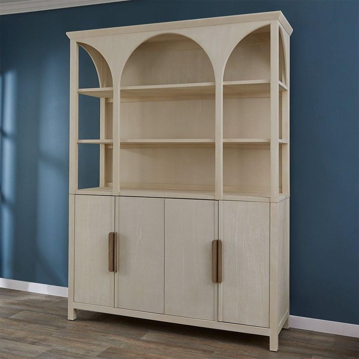 a white bookcase with two doors on the front and one door open to reveal a blue wall