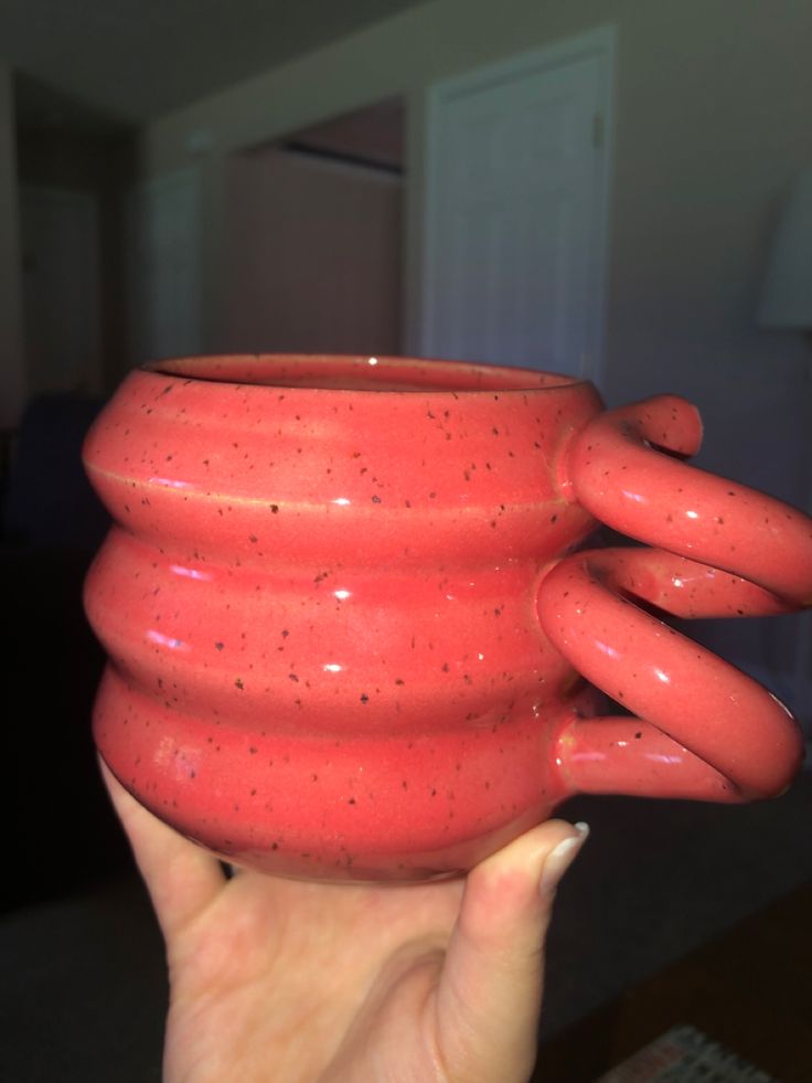 a person holding up a large red vase in their left hand and the top half of it