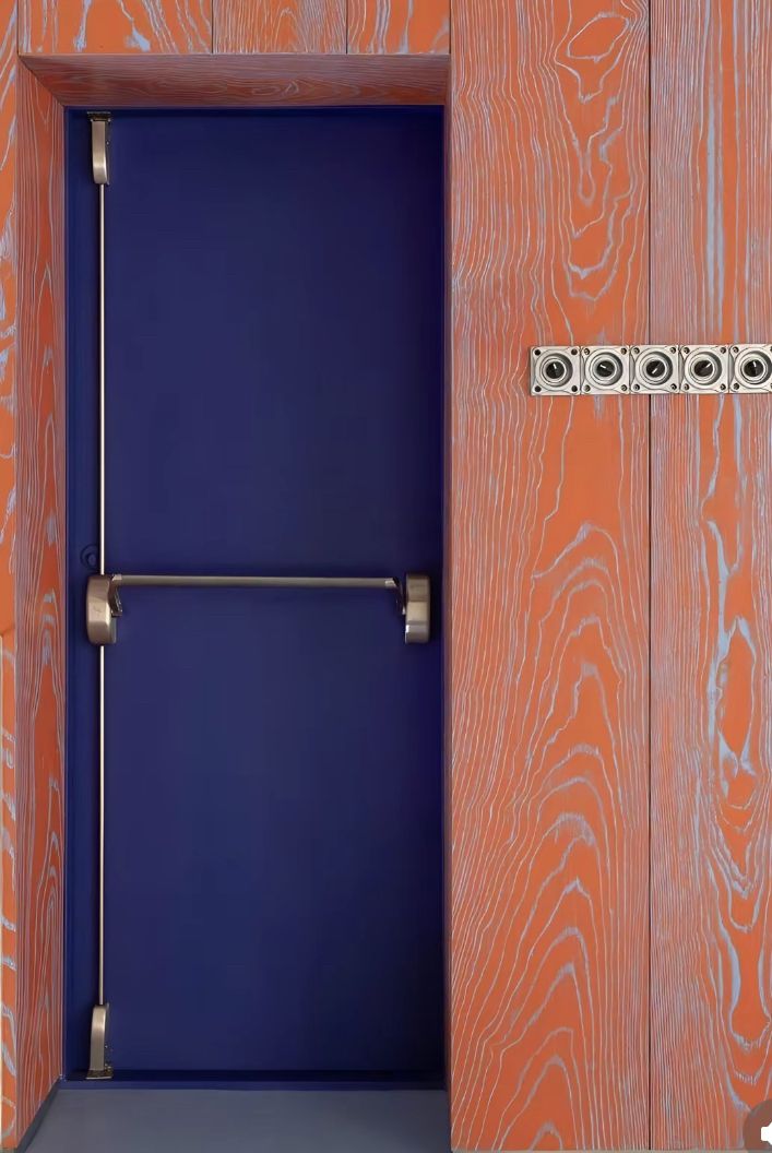 a blue door is in the middle of an orange and white wall with metal handles