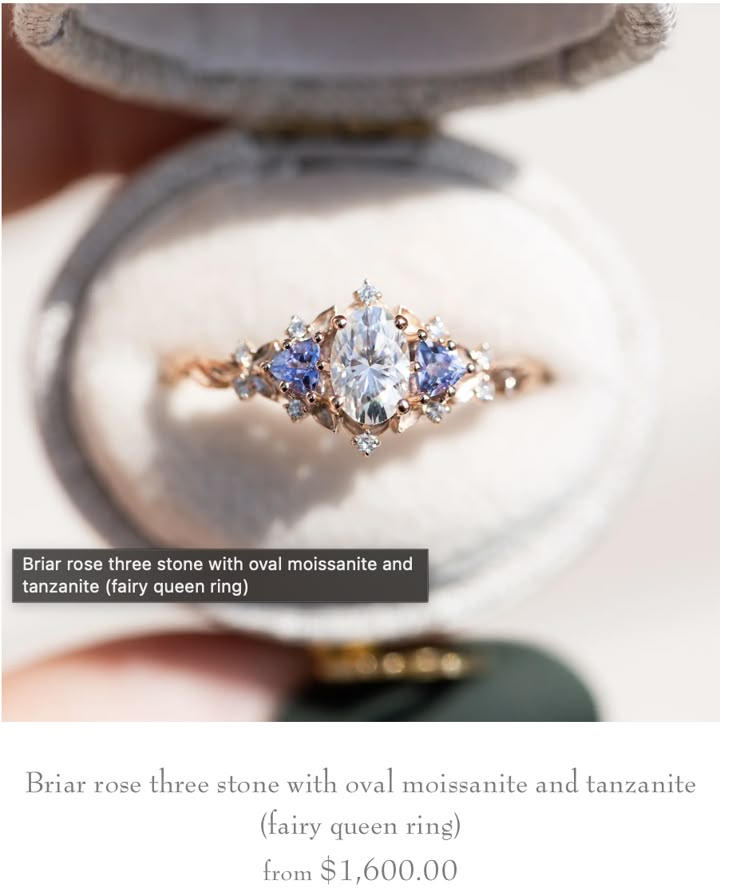 an engagement ring with three blue and white stones in it's presentation box,