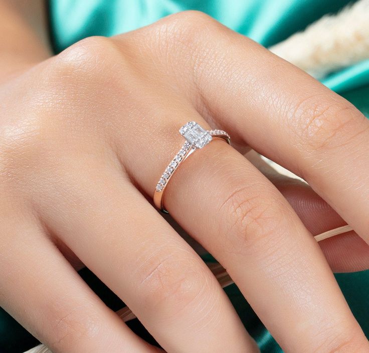 a woman's hand with a diamond ring on top of her finger and an emerald green dress