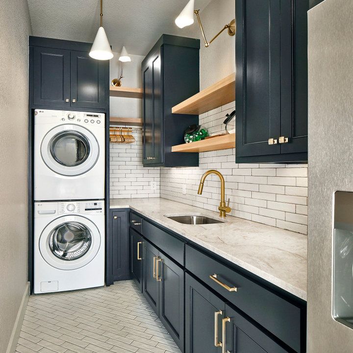 a washer and dryer in a kitchen with dark blue cabinets, white subway tile