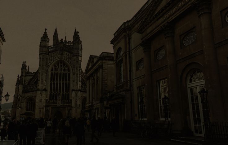 people are walking down the street in front of some old buildings at night with lights on