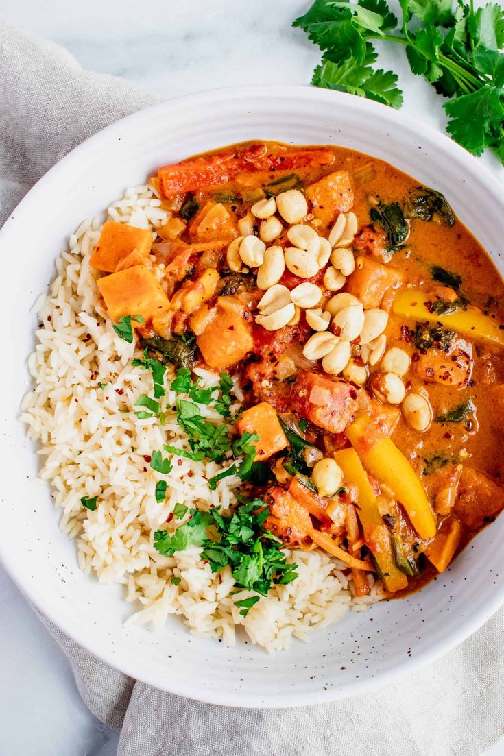 a white bowl filled with rice and vegetables next to garnish on the side