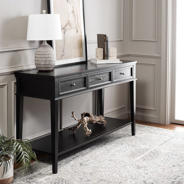 a black console table with two drawers and a lamp on top in a living room