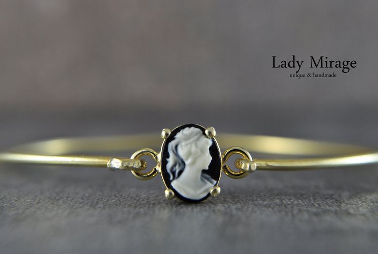 14k gold plated 925 sterling silver bangle. The focus of this bangle is on the small cabochon, which is decorated with a lady cameo. Due to the black background, Lady Cameo comes to the fore with her cream-colored silhouette. Since the cabochon is very fine, the bangle is perfect for everyday use, but also for special events, as its simplicity reflects a certain elegance. The colors create a magical interplay and make the bracelet a very special and romantic piece of jewelry. Treat yourself or make other vintage lovers happy. It is the perfect gift idea for occasions such as birthdays, mother's days or anniversaries. Treat your girlfriend, mother or loved ones to this special piece of jewellery. The matching necklace, earrings and ring or this piece of jewelery as a set can be found under Fine Jewelry Bracelet With Cabochon, Elegant Cameo Jewelry, Elegant Cameo Jewelry For Formal Occasions, Elegant Oval Cameo Jewelry, Fine Jewelry Cabochon Bracelets As Gift, 14k Gold Cameo Jewelry, 14k Gold Cameo Round Jewelry, Cameo 14k Gold Round Jewelry, Elegant Cameo Jewelry For Anniversary