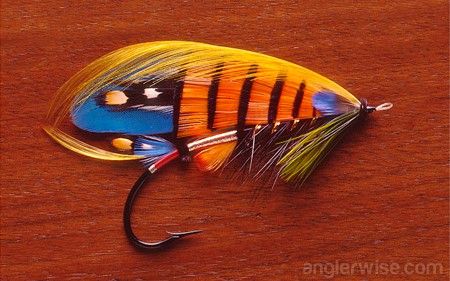 an orange, yellow and blue fishing lure on a wooden surface