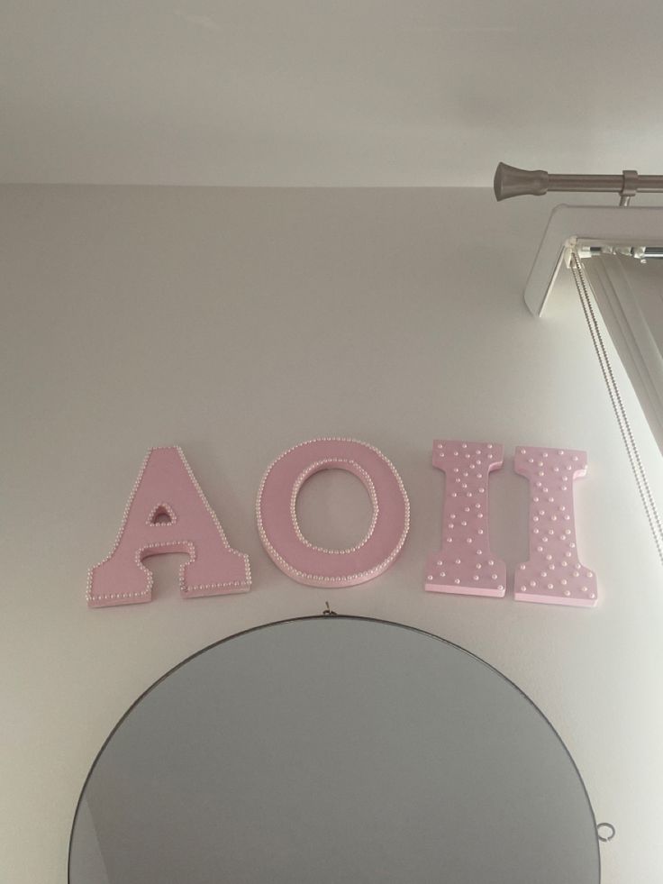 the word aoi spelled out in pink and polka dots sits above a round mirror