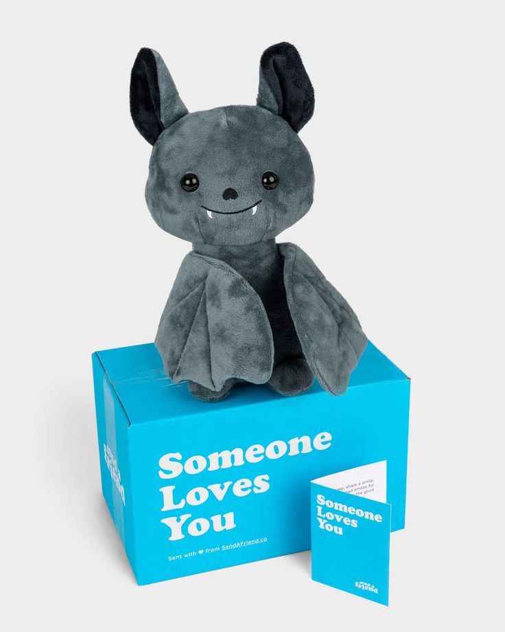 a gray stuffed animal sitting on top of a blue box with someone loves you written on it