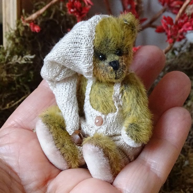 a small teddy bear sitting in someone's hand