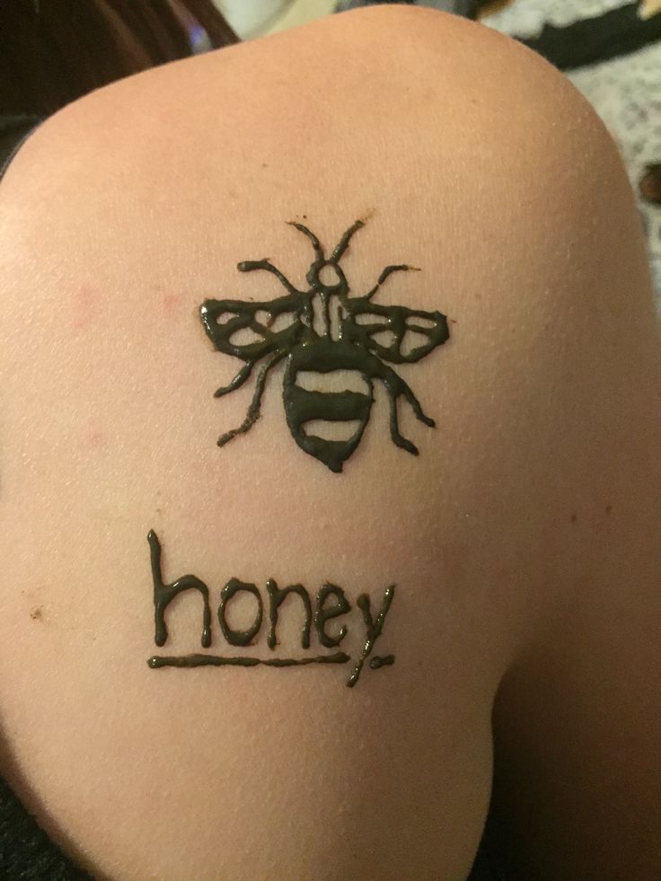 a woman with a tattoo on her back that says honey and a bee in the middle