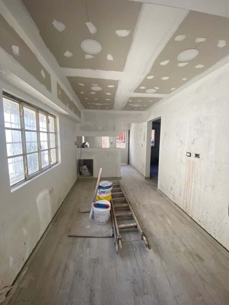 an empty room with paint rollers and buckets on the floor in front of it