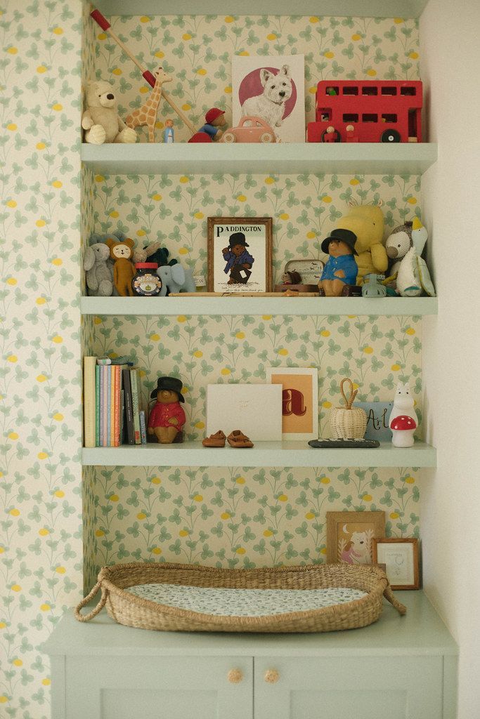 a baby's crib in the corner of a room with wallpapered walls