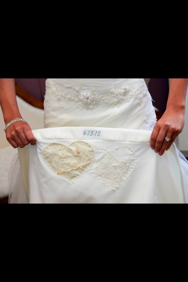 the bride is holding her wedding dress with an embroidered heart on it's sash