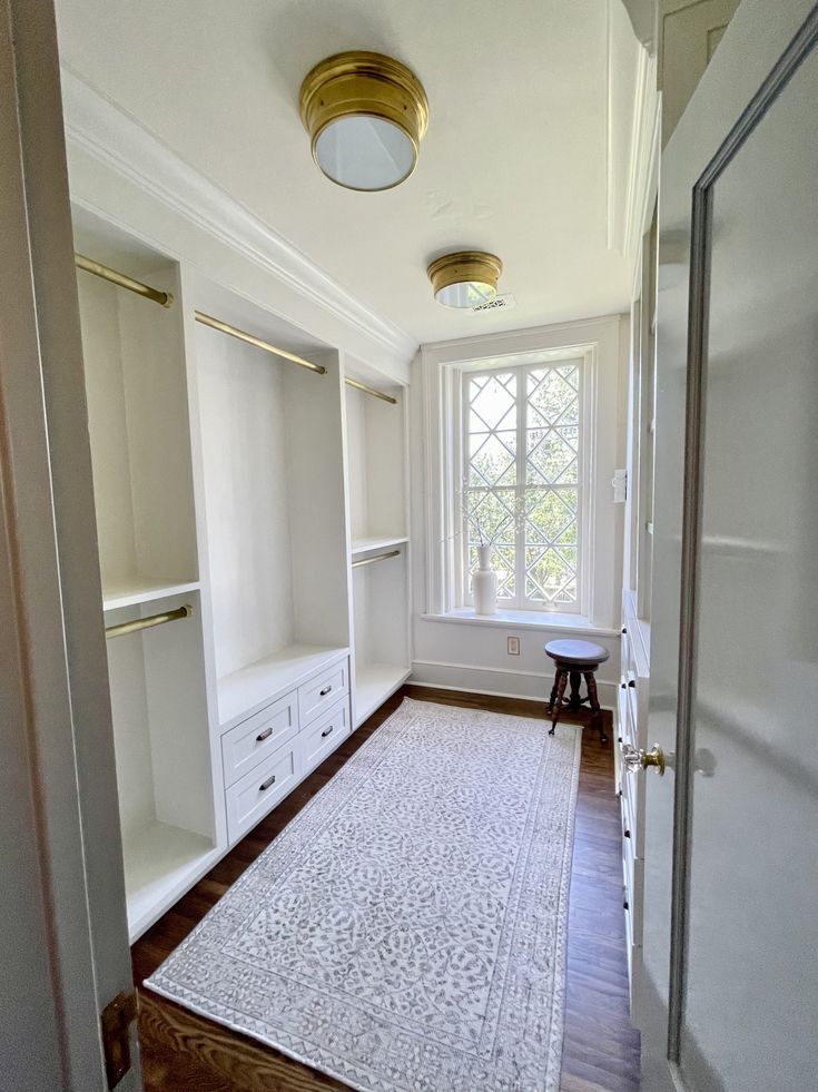 an empty walk in closet with white walls and wood flooring on the other side