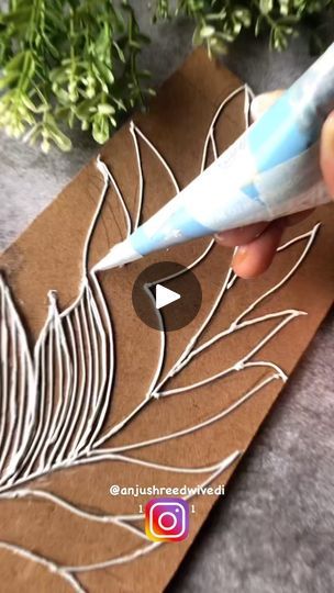 someone is using a pen to cut out leaves on a piece of brown paper with white thread