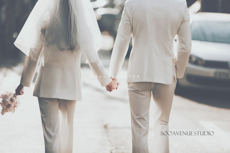 a bride and groom walking down the street holding hands