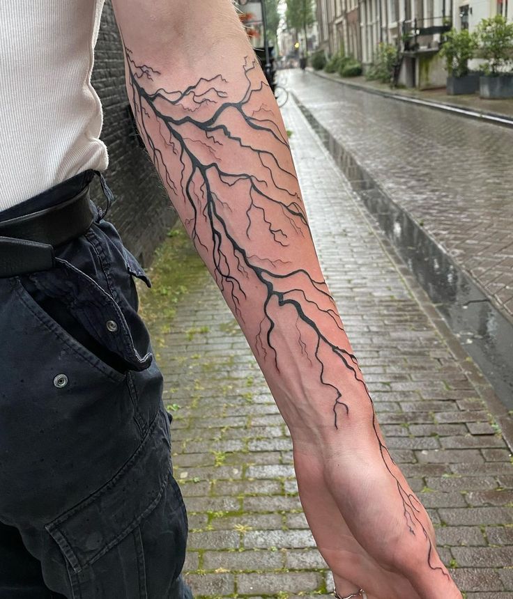 a man with a tattoo on his arm holding an umbrella in front of the street