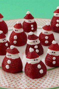 some strawberries with santa hats on them are sitting on a white and green plate