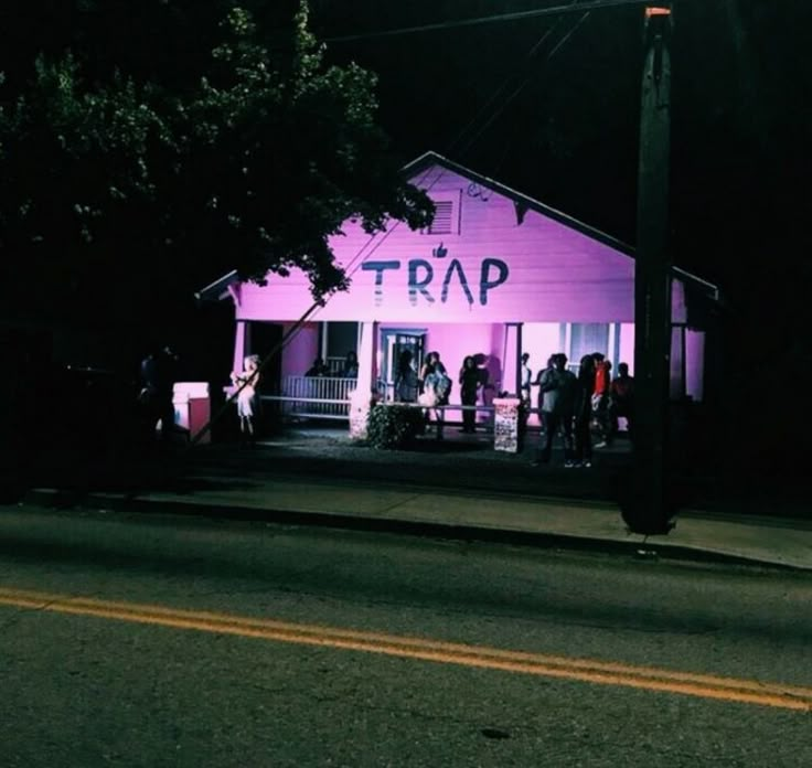 people are standing in front of a pink building with the word trap written on it