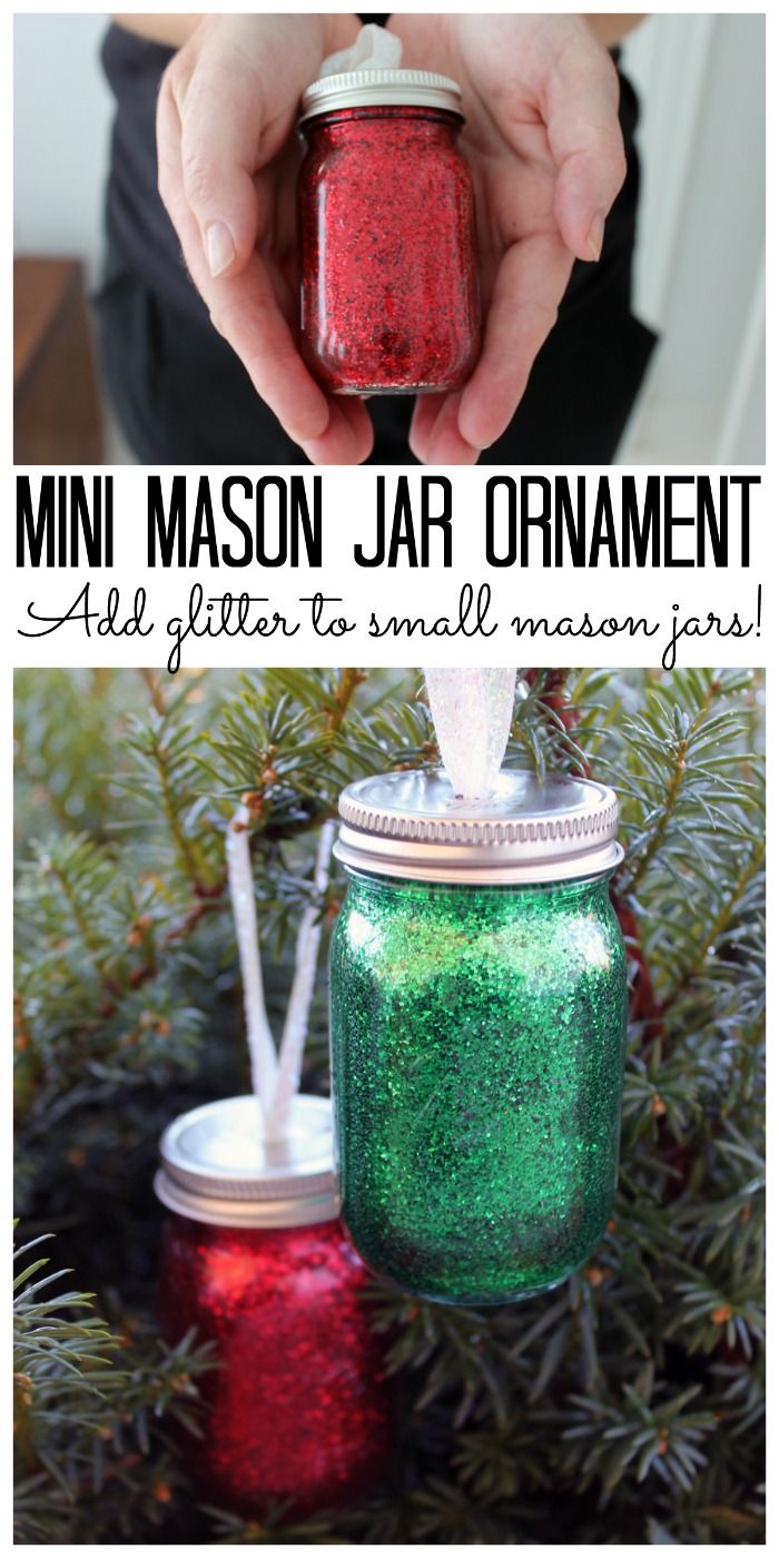 a person holding a mason jar in front of a christmas tree with the words mini mason jar ornament