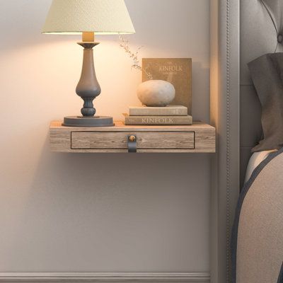 a nightstand with two books on it next to a night stand and lamp in a bedroom