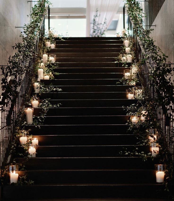 candles are lit on the steps leading up to an indoor wedding ceremony venue with greenery and hanging lanterns