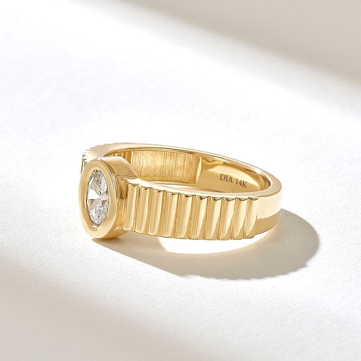 a yellow gold ring with a diamond in the center on a white surface, close up