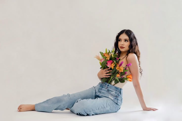 a woman sitting on the floor with flowers in her hands