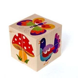 a wooden block with colorful birds and mushrooms painted on the sides, sitting against a white background