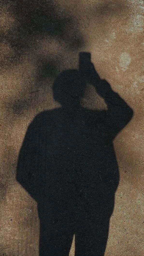 the shadow of a man in a suit and hat