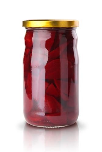 a jar filled with red pickles on top of a white table