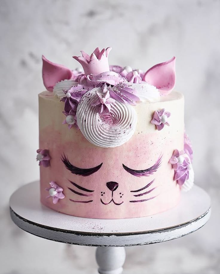 a cake decorated with pink and white frosting has a cat's face on it