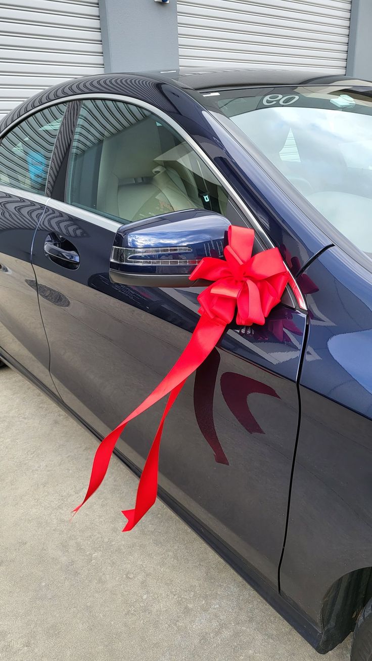 a car with a red ribbon tied to it's side door and the front window