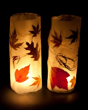 two lit candles decorated with autumn leaves