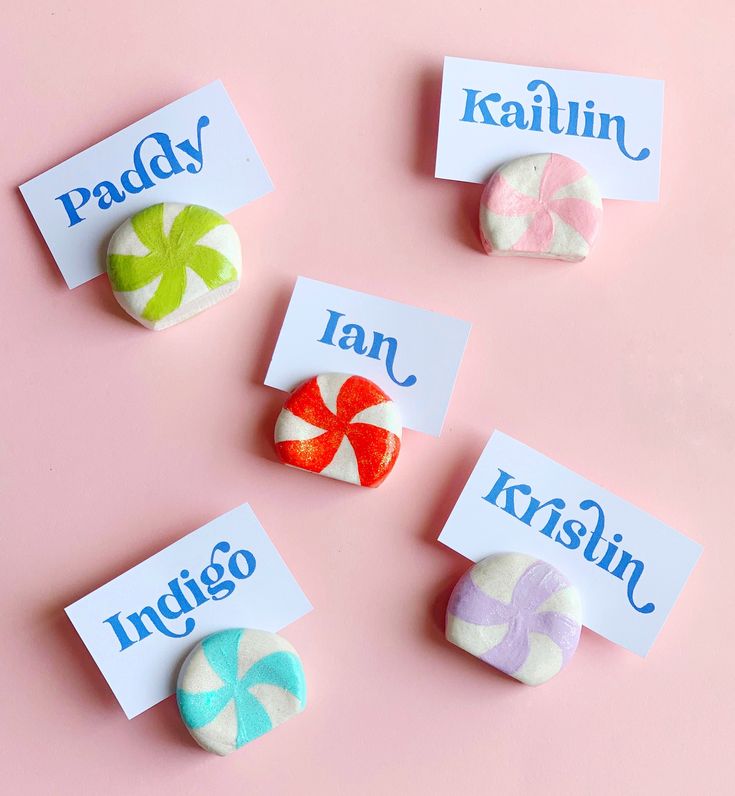 four candy candies with name tags on them sitting next to each other in front of a pink background