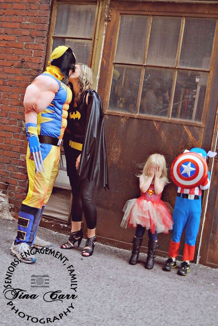 three people dressed up as superheros standing in front of a building with two children