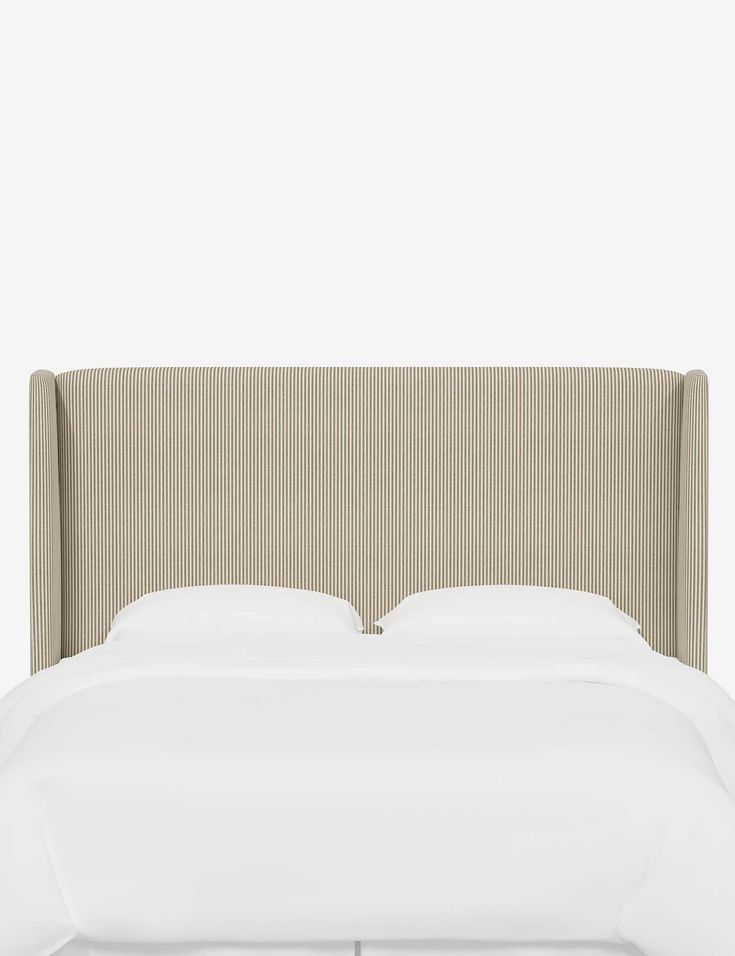 an upholstered headboard with white sheets and pillows