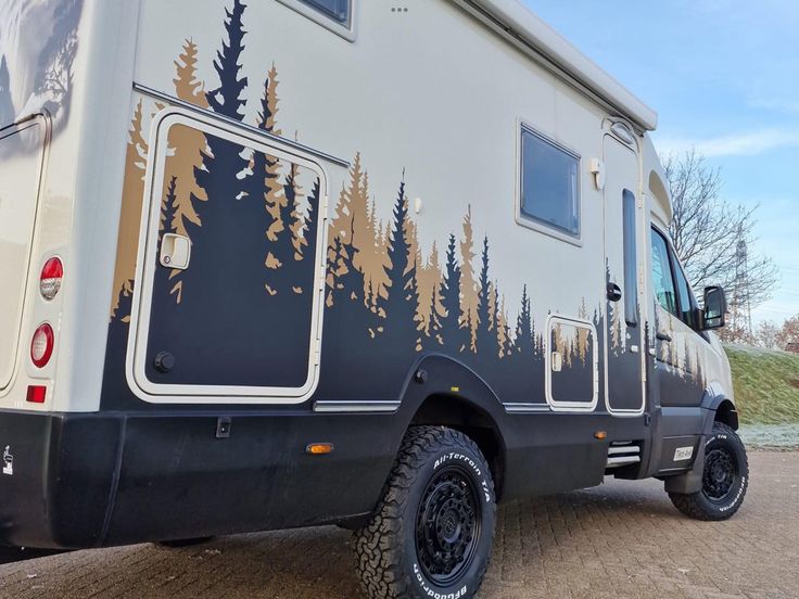 a camper van with trees painted on the side