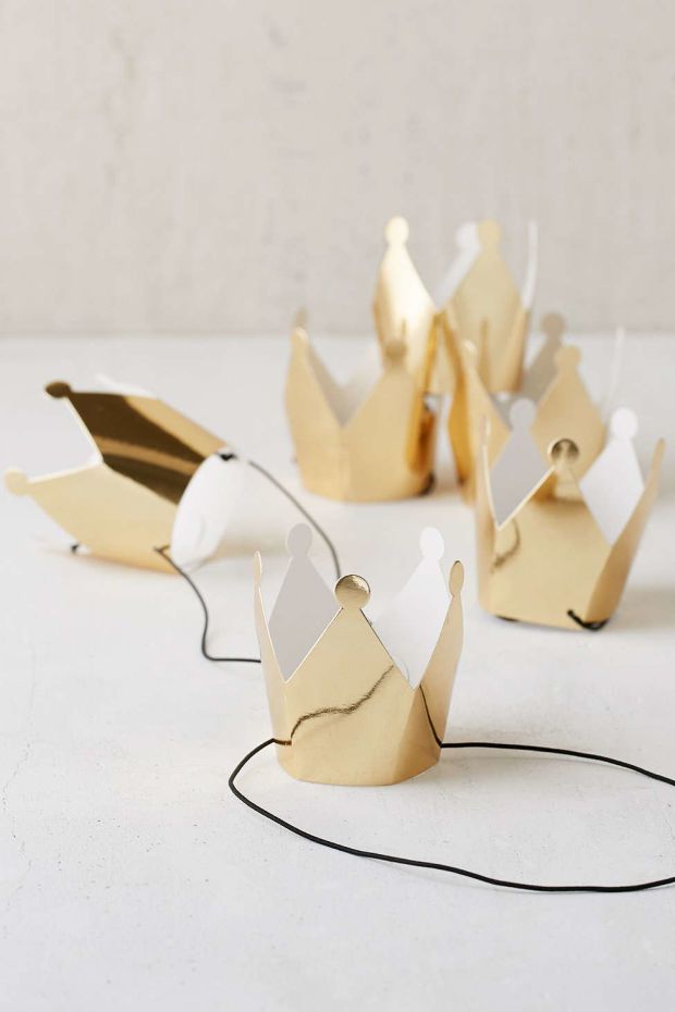 three paper crowns sitting on top of a white table next to a black cord and a wall