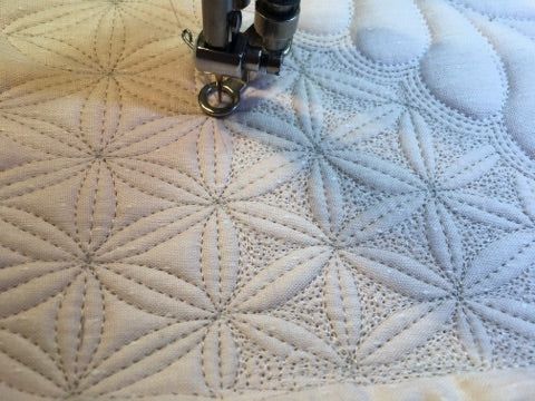 a close up of a bed with a quilt on it and two sewing needles in the middle