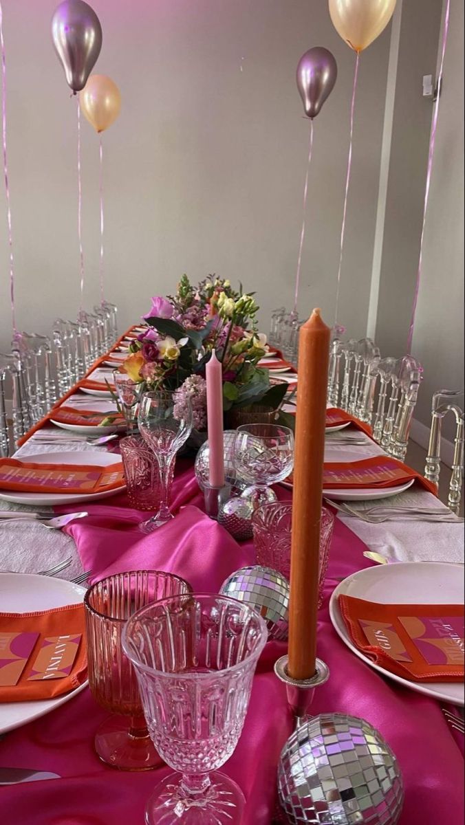 the table is set with plates, silverware and pink napkins for a party