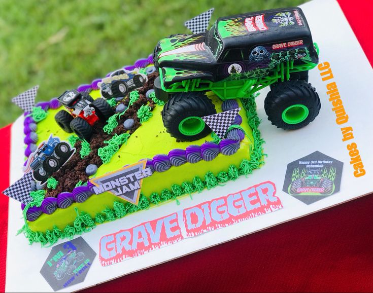 a monster truck cake on top of a sheet cake with green frosting and purple icing